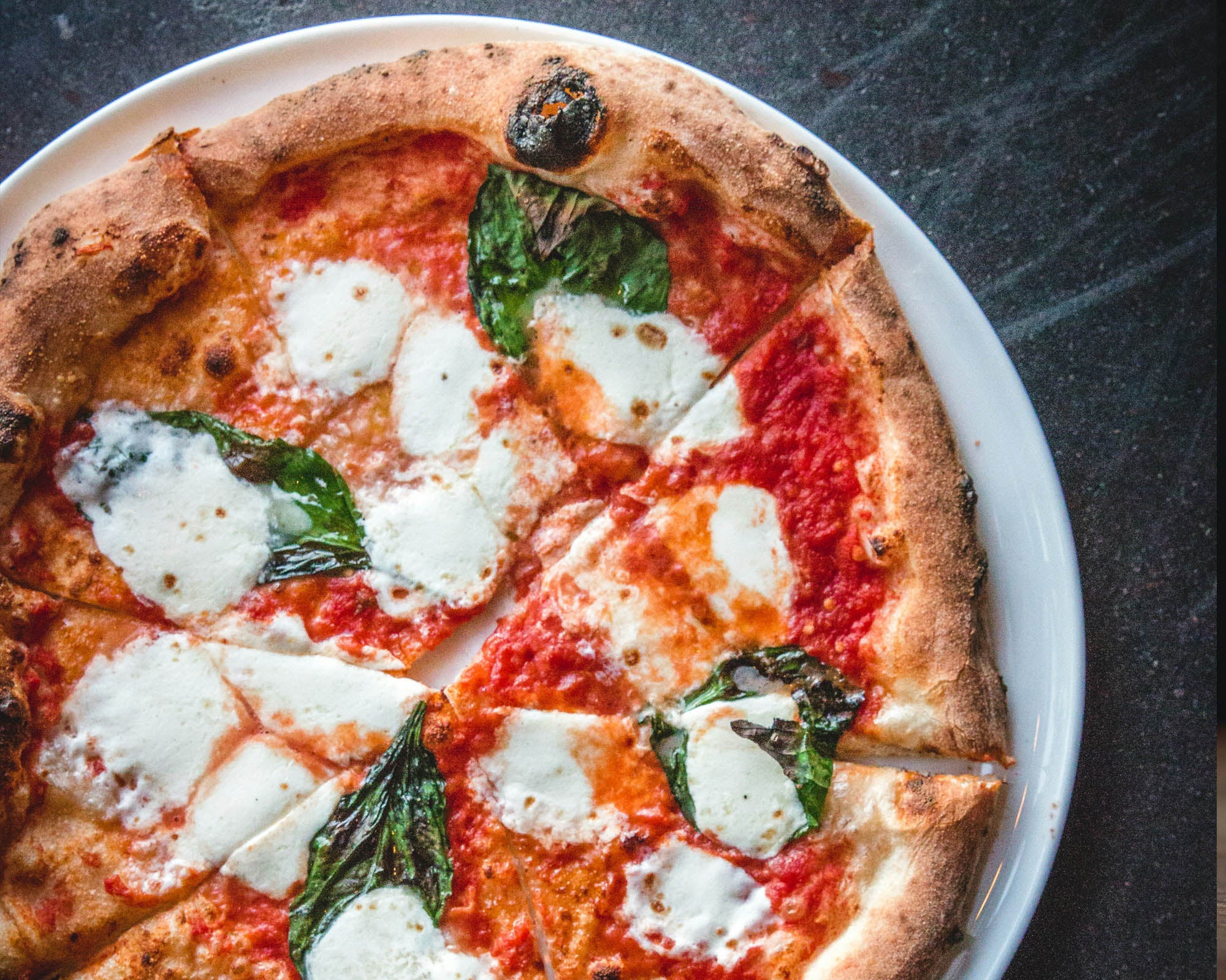 Margherita pizza with mozzarella and basil on a white plate