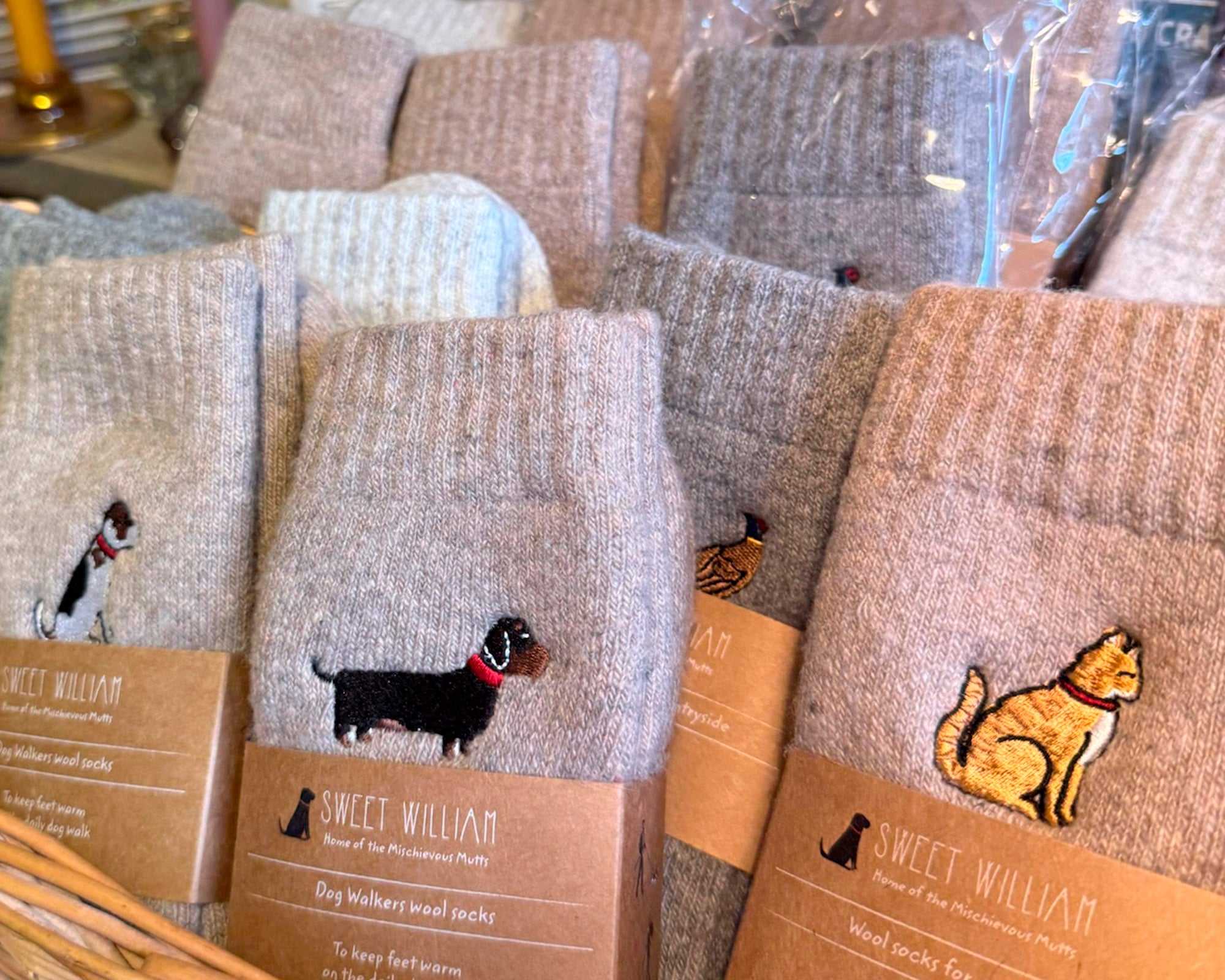 Row of socks with embroidered animals on packaging, displayed in a store setting.